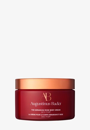 Augustinus Bader Geranium Rose Body Cream in einem roten Glas mit kupferfarbenem Deckel, mit goldener und weißer Beschriftung auf der Vorderseite.