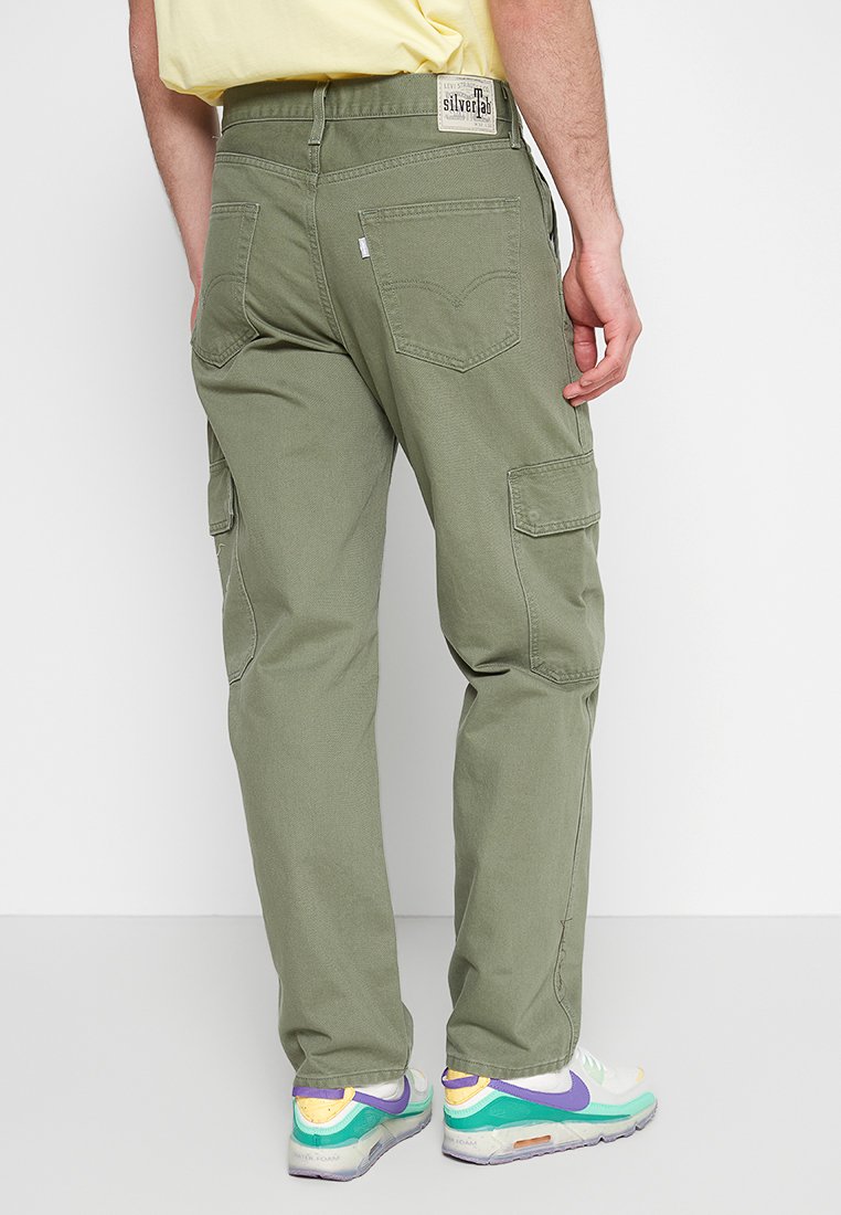 Pantalons cargo vert olive avec plusieurs poches, coupe droite et tissu texturé. Présente une étiquette sur la ceinture arrière.