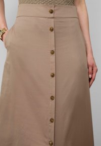 Khakifarbener Midirock mit einer Knopfleiste vorne, zwei Seiten pockets und einer glatten Textur, mit einer taillierten Silhouette und schlichtem Design.