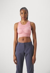 Sujetador deportivo corto rosa con un patrón texturizado y un ajuste ceñido, combinado con pantalones de rendimiento azul marino. Ambas prendas están fabricadas con tela elástica.