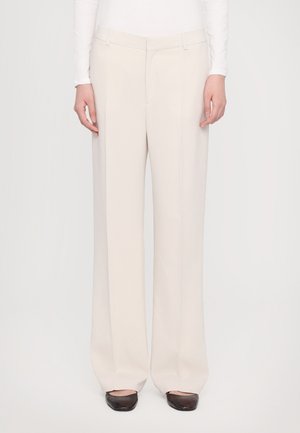 Bequeme weit geschnittene Hose aus leichtem beigen Stoff, mit flachem Bund, seitlichen Taschen und tailliertem Schnitt. Glatte Textur und klare Linien.