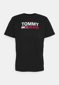 Černé bavlněné tričko s výrazným bílým a červeným logem "TOMMY JEANS" na přední straně, s klasickým kulatým výstřihem a krátkými rukávy.