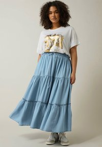 Falda midi de tiras en azul claro con cinturilla elástica y cordón, combinada con una camiseta blanca con un gráfico floral metálico.