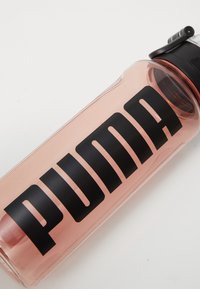 Heldere plastic waterfles met een roze tint, voorzien van een opvallend zwart "PUMA" logo aan de zijkant en een zwarte deksel met een tuit.