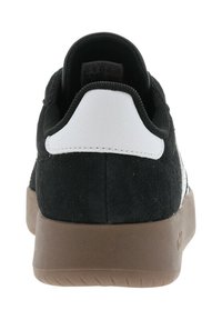 Sneaker in suede nero con linguetta bianca sul tallone e suola in gomma marrone. Presenta un collo imbottito e un design testurizzato sul retro. Fabbricato in Myanmar.