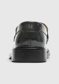 Černá lakovaná obuv s elegantním designem, hladkým povrchem a nízkým dřevěným podpatkem. Uzavřená pata s detailním prošíváním a zaobleným tvarem.