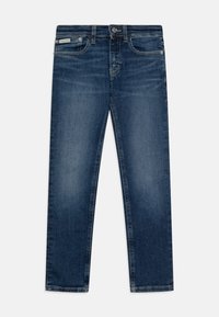 Sötétkék farmernadrág slim fit fazonban, öt zsebbel és cipzáros belebújással. Finom elhalványulásokkal és egy kis márkacímkével a derekán.