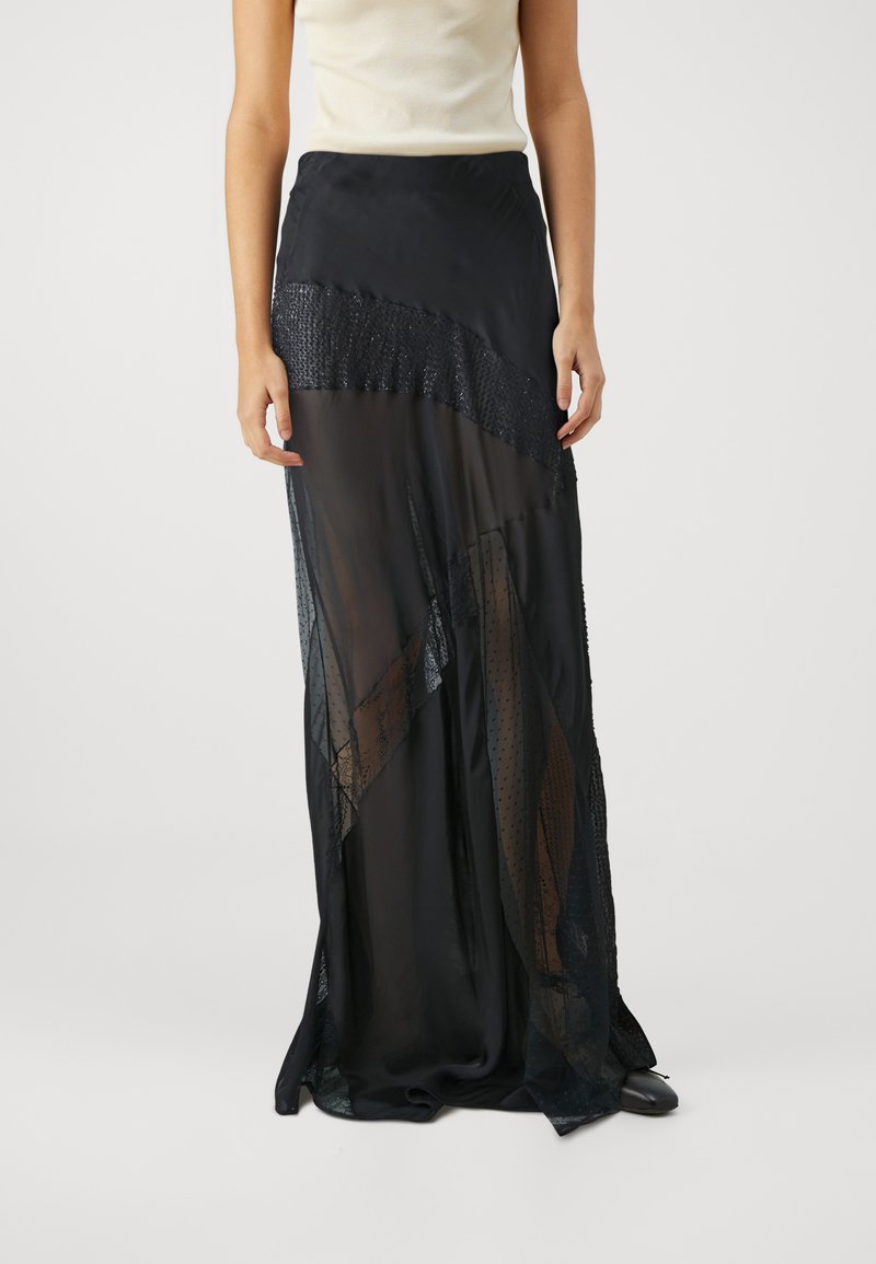 Jupe maxi noire avec un design en couches comprenant des panneaux transparents et texturés, ornée d'une ceinture à perles et d'un élégant tombé.