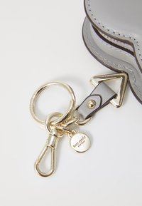 Accessorio in pelle grigia per portachiavi con hardware dorato, presenta un anello portachiavi circolare, una striscia in pelle e un'etichetta metallica incisa con "kate spade."