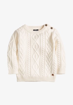 Suéter de punto canalé color crema con mangas largas y dos botones marrones en el hombro izquierdo, puños y borde acanalados.