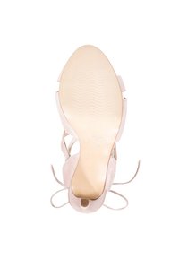 Sandal da donna in suede beige che mostra la suola testurizzata e le cinghie alla caviglia, vista dal basso.