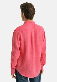 Camicia di lino rosa a maniche lunghe con colletto bottonato, piega sul retro e orlo curvo. Vestibilità casual, tessuto testurizzato e maniche dritte con polsini.
