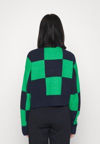 Häkelpullover mit grün-blauem Karomuster, kurzem Design, strukturierter Stoff und überschnittenen Schultern.