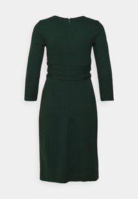 Ciemnozielona, długa sukienka z długim rękawem i okrągłym dekoltem, z marszczonymi detalami po bokach oraz zamkiem błyskawicznym z tyłu. Gładki, dopasowany materiał.