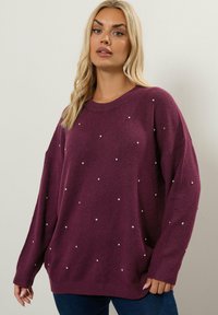 Luonnonvärinen neulepaita, jossa on löysä istuvuus, pyöreä kaula-aukko ja pitkät hihat. Koristeena on epäsäännöllisesti aseteltuja strasseja. Pehmeä rakenne, rento muotoilu.