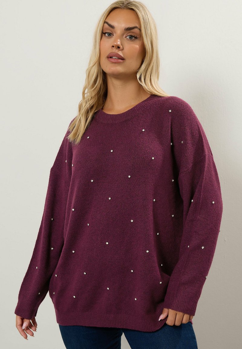 Luonnonvärinen neulepaita, jossa on löysä istuvuus, pyöreä kaula-aukko ja pitkät hihat. Koristeena on epäsäännöllisesti aseteltuja strasseja. Pehmeä rakenne, rento muotoilu.