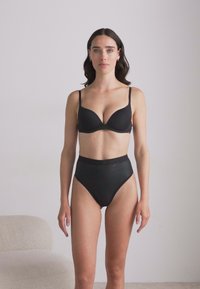 Svart bh og høy tights truser. Bh-en har glatt stoff; trusene har subtile horisontale striper og en myk midjebånd.
