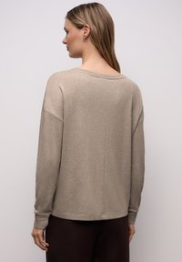 Beiger, locker sitzender Pullover mit weitem Ausschnitt, überschnittenen Schulternähten und gerippten Bündchen. Weiche Textur mit glattem Finish und ohne Muster.
