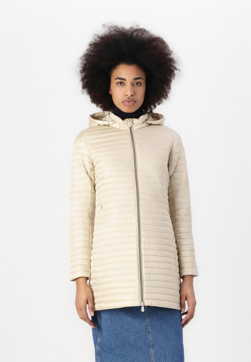 Beige gewatteerde jas met een aansluitende capuchon, volledige ritssluiting en lange mouwen. Soepele, lichtgewicht stof met horizontale stiksels.