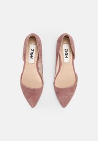 Chaussures en cuir suédé rose à bout pointu avec un design à dos ouvert et un marquage minimaliste sur la semelle intérieure, mettant en avant une texture lisse et une silhouette élégante.