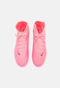 Svijetloružičaste nogometne kopačke s teksturiranom površinom, dizajnom na vezivanje i crnim Nike swoosh logotipom s vanjske strane. Visoka verzija.