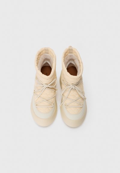 Beige quilted ankle high boots with rounded toes and beige laces, shown from above on a plain light background.