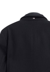 Czarny płaszcz z wyciętym kołnierzem, teksturowana tkanina, z pojedynczym szwem na środku z tyłu. Posiada małą metkę marki przy szyi.