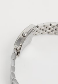 Sølv rustfritt stål armbåndsur med rektangulært hus, en polert bezel og en lenkearmbånd. Har en krone for tidsetting.