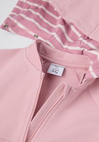 Rosa Babyjacke mit Reißverschluss und gestreiftem Innenfutter. Der Stoff hat eine glatte Textur und Druckknöpfe sind am Saum angebracht.