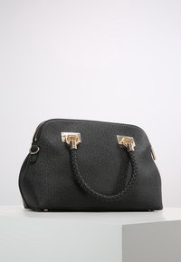 Zwarte synthetische handtas met een gestructureerde afwerking, gevlochten handgreep, gouden hardware accenten en een ritssluiting. Compacte, gestructureerde vorm.