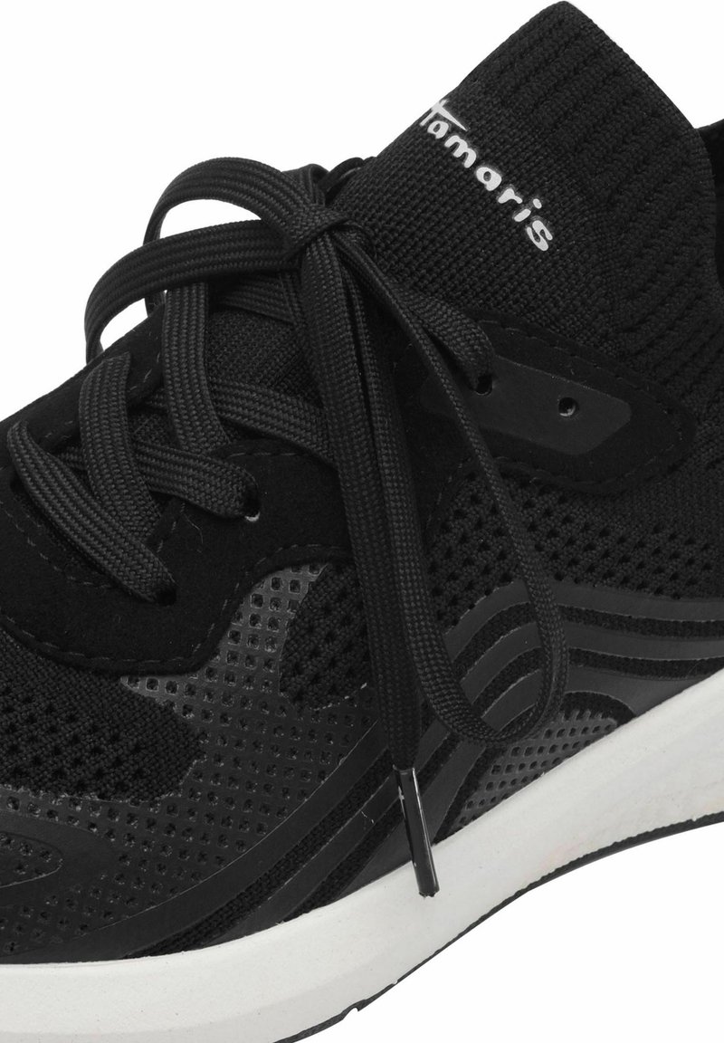 Schwarzer Sportschuh aus Mesh und Wildleder, mit runder Zehenpartie, geripptem Kragen, traditioneller Schnürung und einer weißen Zwischensohle mit dezenten schwarzen Akzenten.