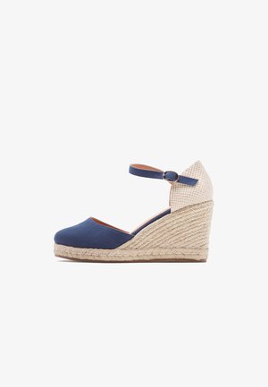 Scarpe con zeppa in tela blu navy, con tacco in juta intrecciata e cinturino alla caviglia. Il tacco presenta un accento in tessuto beige testurizzato.