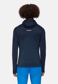 Navyblaue Langarm-Hoodie mit strukturiertem Muster, kontrastierenden Nähten und einem Logo auf dem Rücken nahe dem Ausschnitt.
