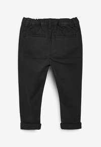 Pantalons en coton noir avec une coupe ajustée, taille élastique et ourlets à revers. Comprend deux poches arrière et une texture lisse.