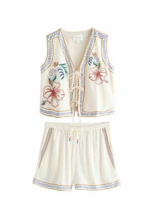 Ensemble deux pièces comprenant un gilet crème avec broderies florales, un lacement à l'avant et un short assorti avec des finitions décoratives et des poches.
