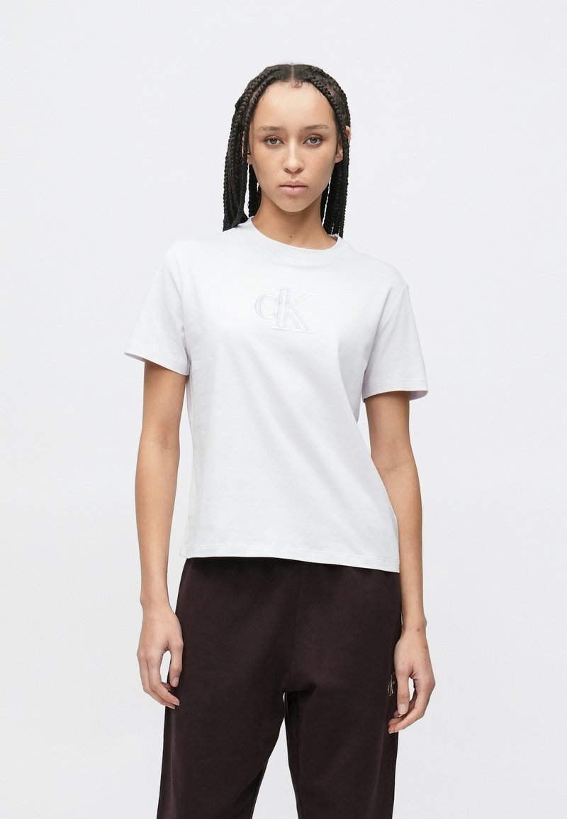 Tricou alb din bumbac cu mâneci scurte și decolteu rotund, având un logo brodat „CK” pe partea din față. Croială lejeră.