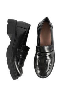 Scarpe in vernice nera con punta arrotondata, dettagli a pieghe nella parte anteriore e suola piatta in gomma. Presentano una cinghia decorativa sopra il collo del piede.