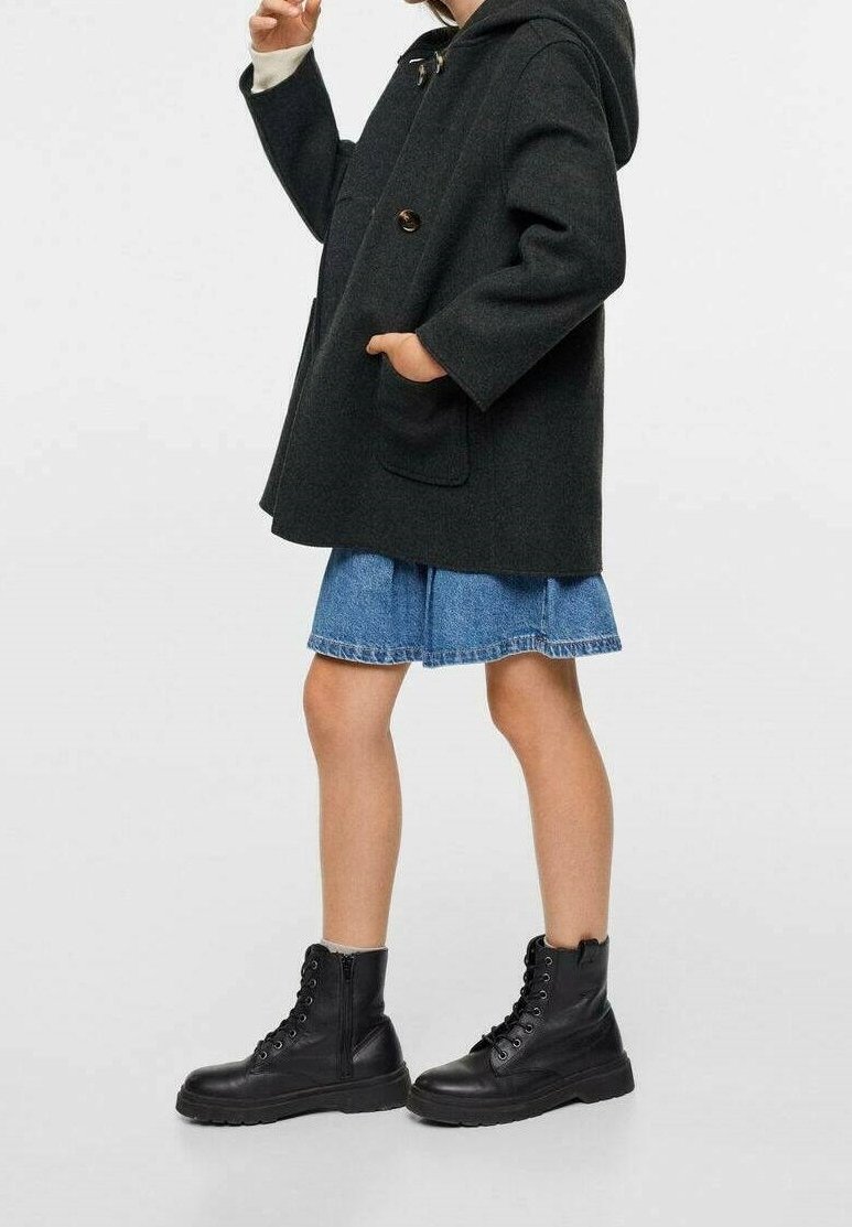 Mörkgrå ullkappa med huva, oversized passform, knappstängning, två fickor; blå denimkjol med utsvängd nederdel; svarta snörstövlar med tjocka sulor.