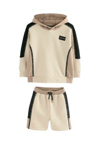 Sudadera con capucha en beige y negro, con mangas en contraste y parche de logo, combinada con pantalones cortos beige a juego que incluyen cordón y bolsillos laterales.