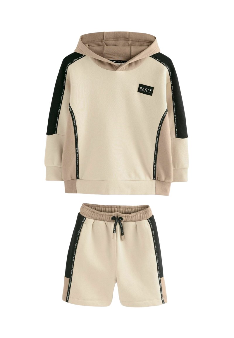 Sudadera con capucha en beige y negro, con mangas en contraste y parche de logo, combinada con pantalones cortos beige a juego que incluyen cordón y bolsillos laterales.