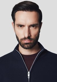 Granatowy sweter na zamek z żeberkowym kołnierzem, noszony na bordowej bluzie typu crew neck. Teksturalna dzianina z detalem w postaci srebrnego zamka.