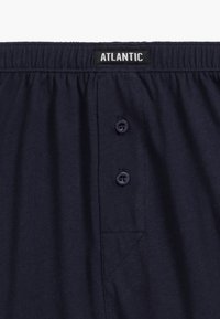 Granatowe bawełniane szorty z elastycznym pasem, z dwoma przednimi guzikami i małym, ukośnym detalem kieszonki. Metka informacyjna nosi napis "ATLANTIC."