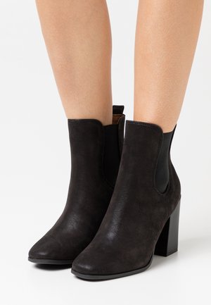Sorte ankelstøvler lavet af ruskind, med spids tå, elastiske sidepaneler og en kraftig blokhæl. Glat tekstur og minimalistisk design.