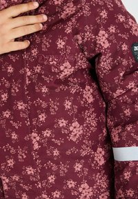 Bordeauxkleurige jas met bloemenprint met roze bloemen, gestructureerde stof, ZigZag-logo en een reflecterende accent op de mouw.