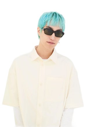 Cream short-sleeve button-up shirt with a chest pocket; worn over a white long-sleeve shirt. Model has blue hair and wears dark sunglasses.