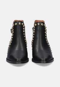 Botas de tobillo de cuero negro con detalles de tachuelas doradas a lo largo de los lados, puntera redonda y un tacón bajo. Acento de hebilla en el tobillo.