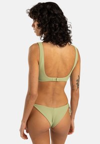 Green ribbed bikini set featuring a scoop back top with adjustable clasp and low-rise bottoms with side tie details.