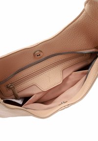 Bežīgas ādas rokassomu iekšpuse ar strukturētu virsmu. Iekļauj centrālo rāvējslēdzēja kabatu un vairākas nodalījumu, izklāta ar mīkstu audumu.