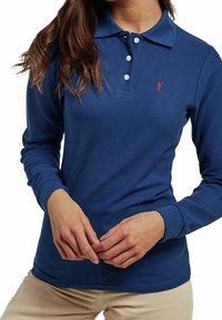 Granatowa bawełniana koszulka polo z długim rękawem, z trzema guzikami przy plisie, prążkowanym kołnierzykiem i czerwonym logo na lewej piersi.