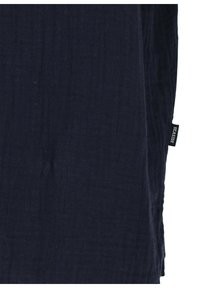 Tissu de muslin bleu marine avec une finition légèrement texturée, comportant une petite étiquette noire sur le côté marquée "SEASIDE."